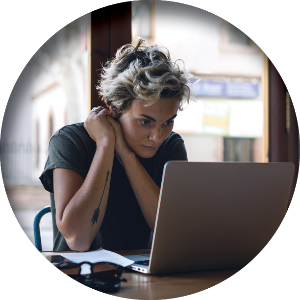 woman leaning on elbows intently looking at laptop screen
